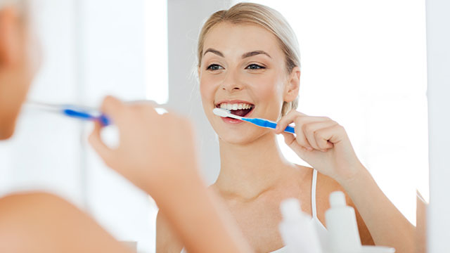 woman-brushes-her-teeth-while-smiling